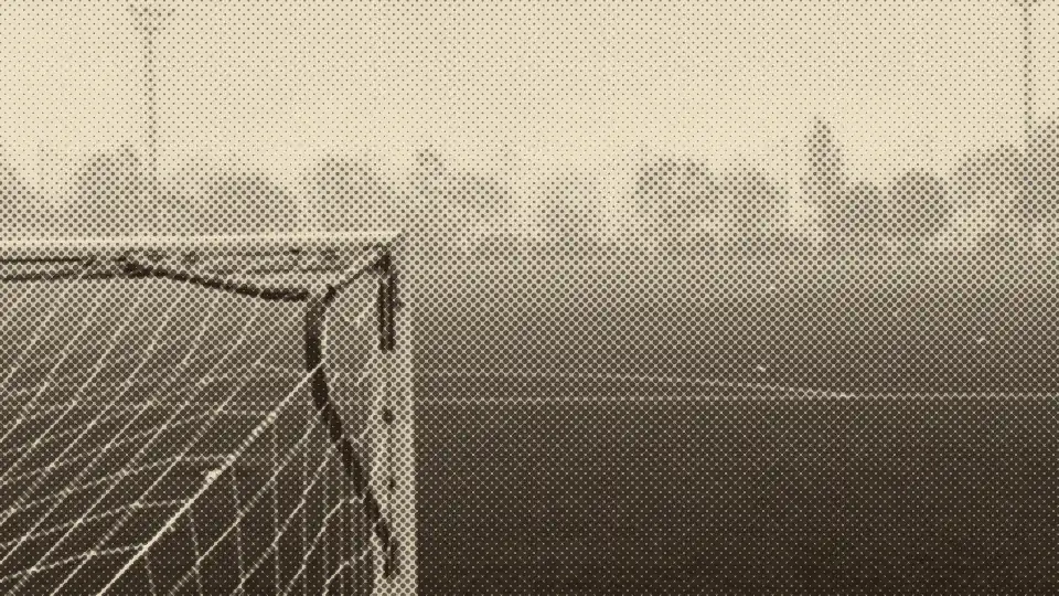 Portería vacía en un campo con niebla